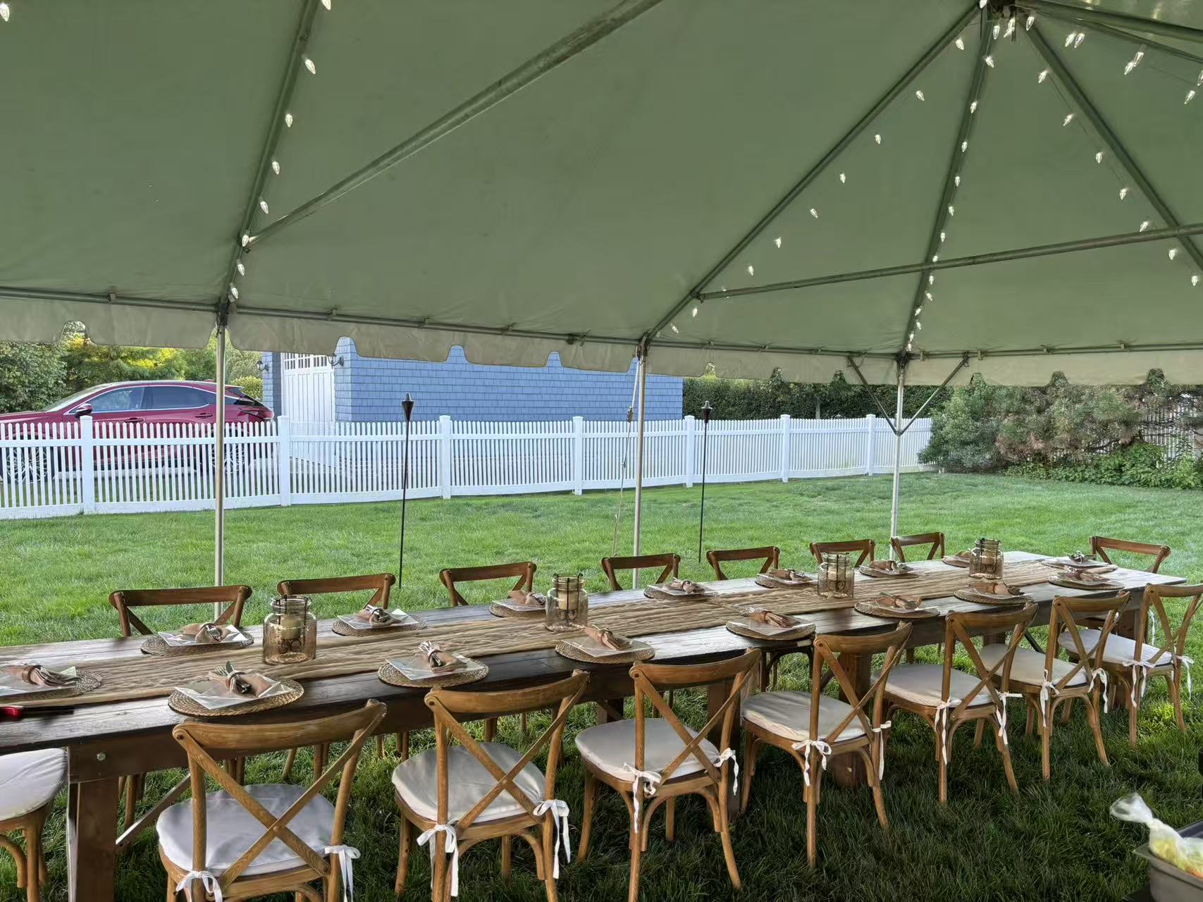 Backyard tent with wooden farm table place settings